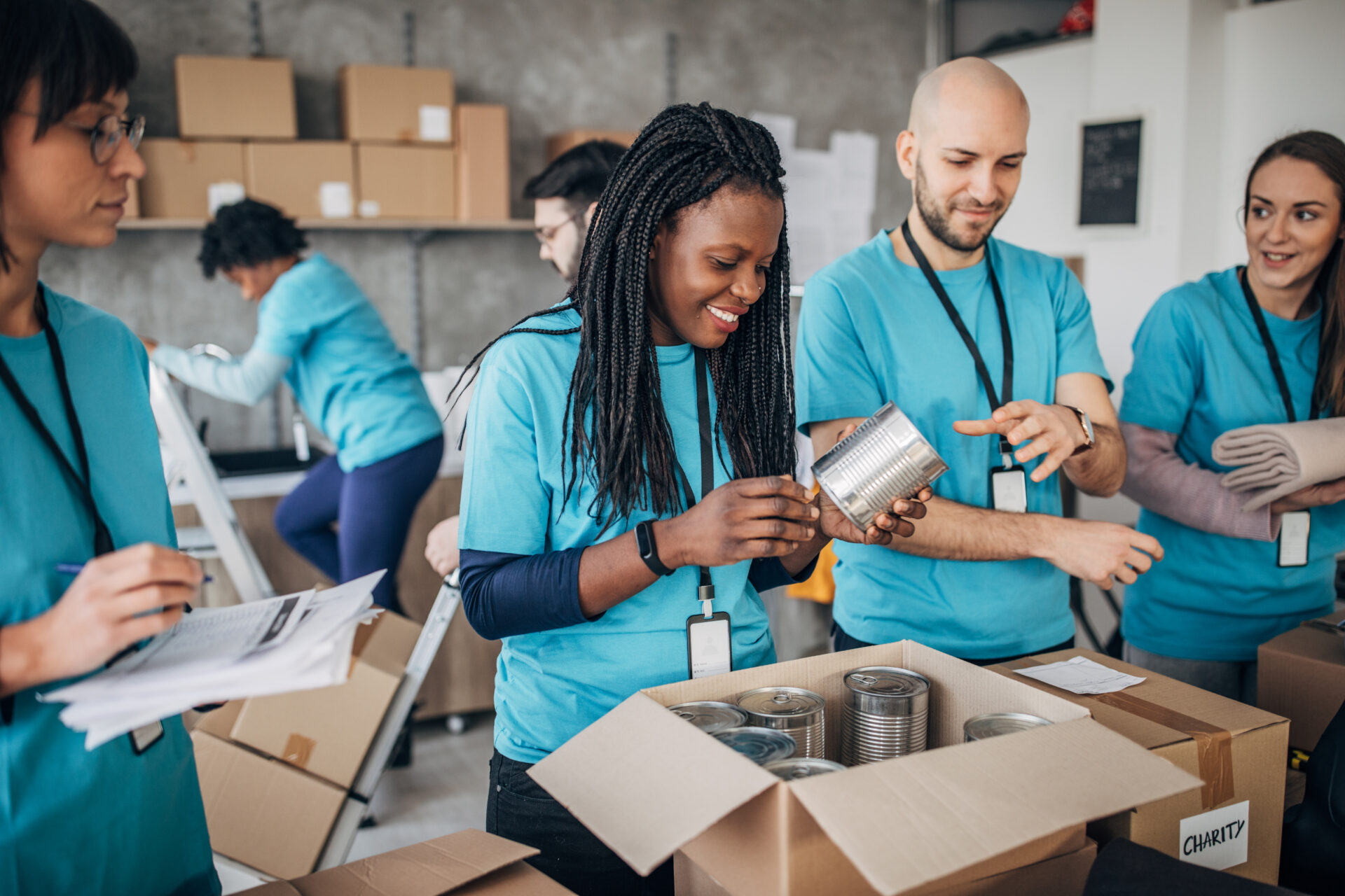 Multi-ethnic group of people, diverse volunteers packing donation boxes in charity food bank.